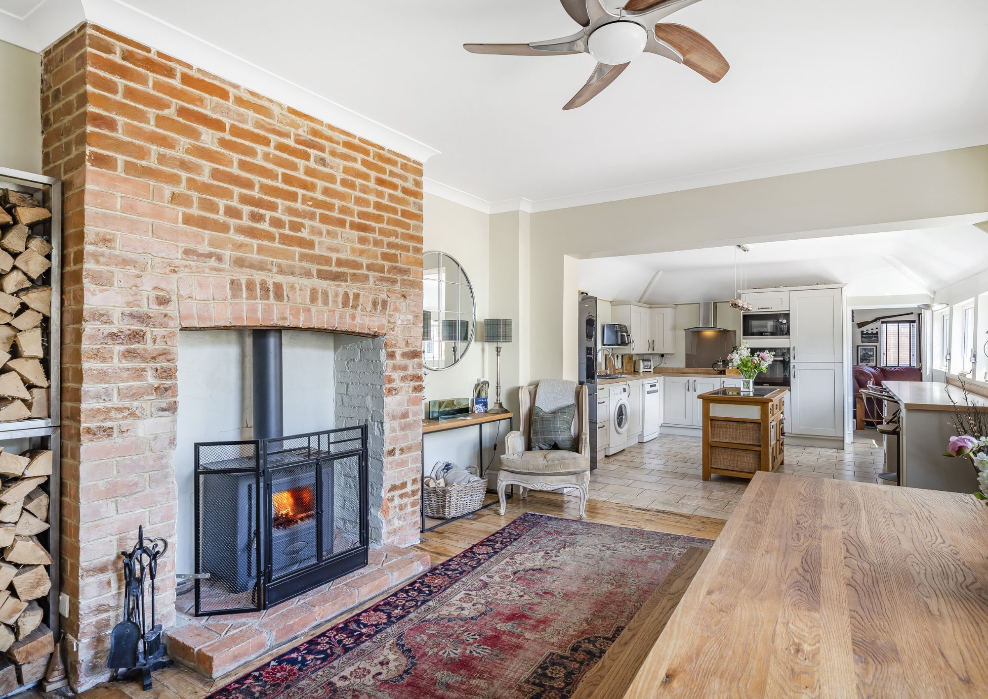A large, open plan kitchen/dining room with a traditional style kitchen and a separate dining area with fireplace and a woodburner