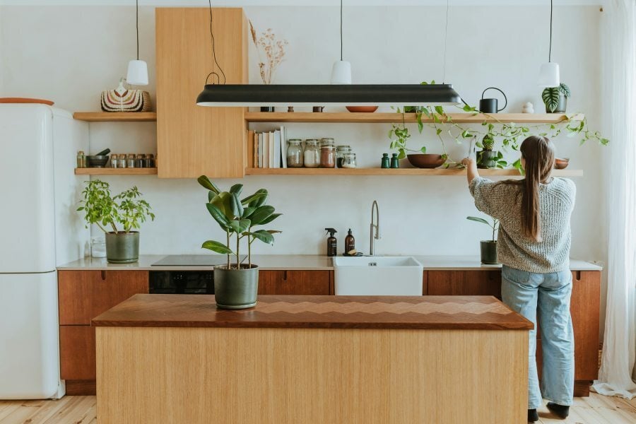 woman in kitchen reaching for shelves