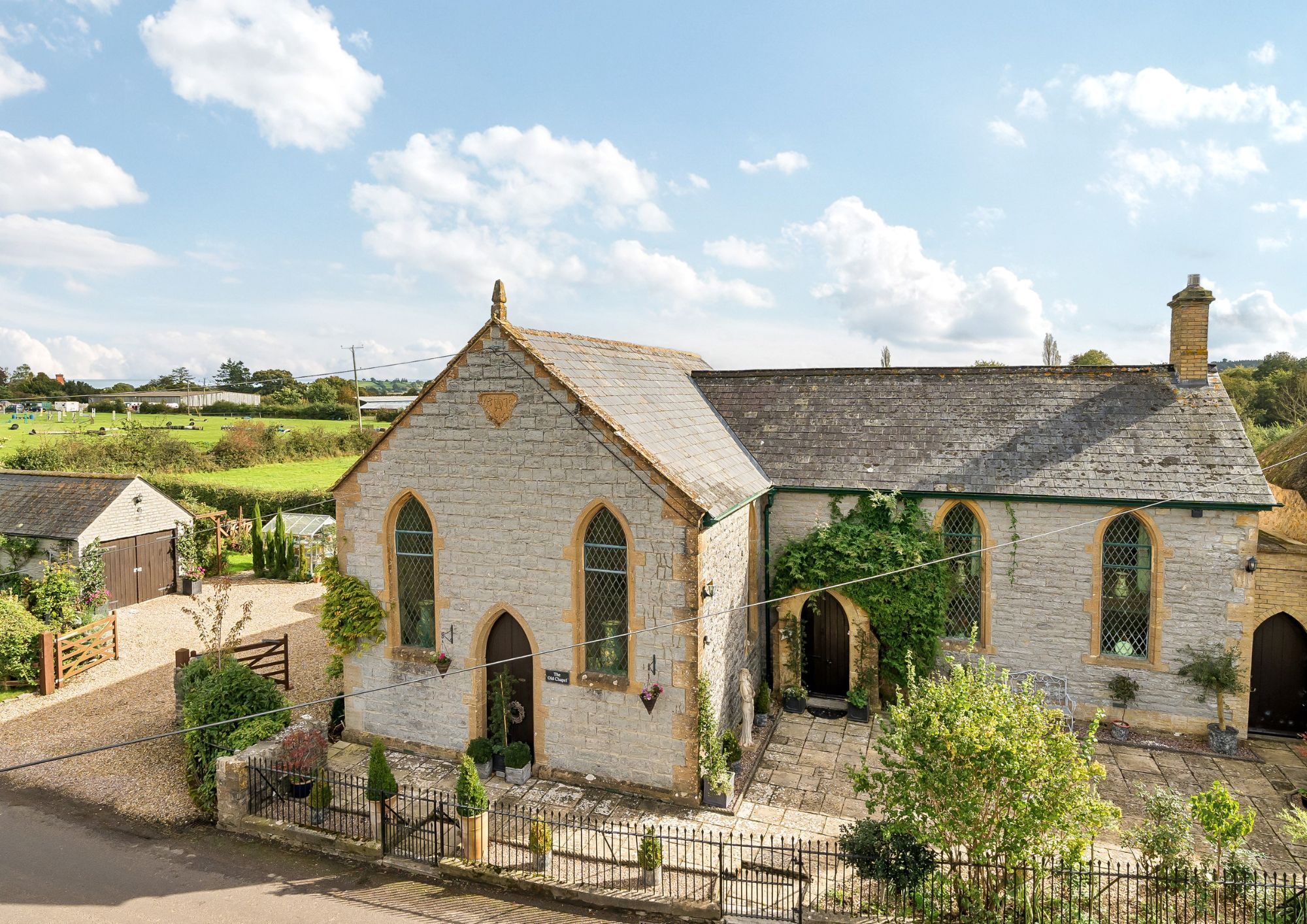 An elevated view of a converted chapel made of Blue Lias stone on a sunny day.