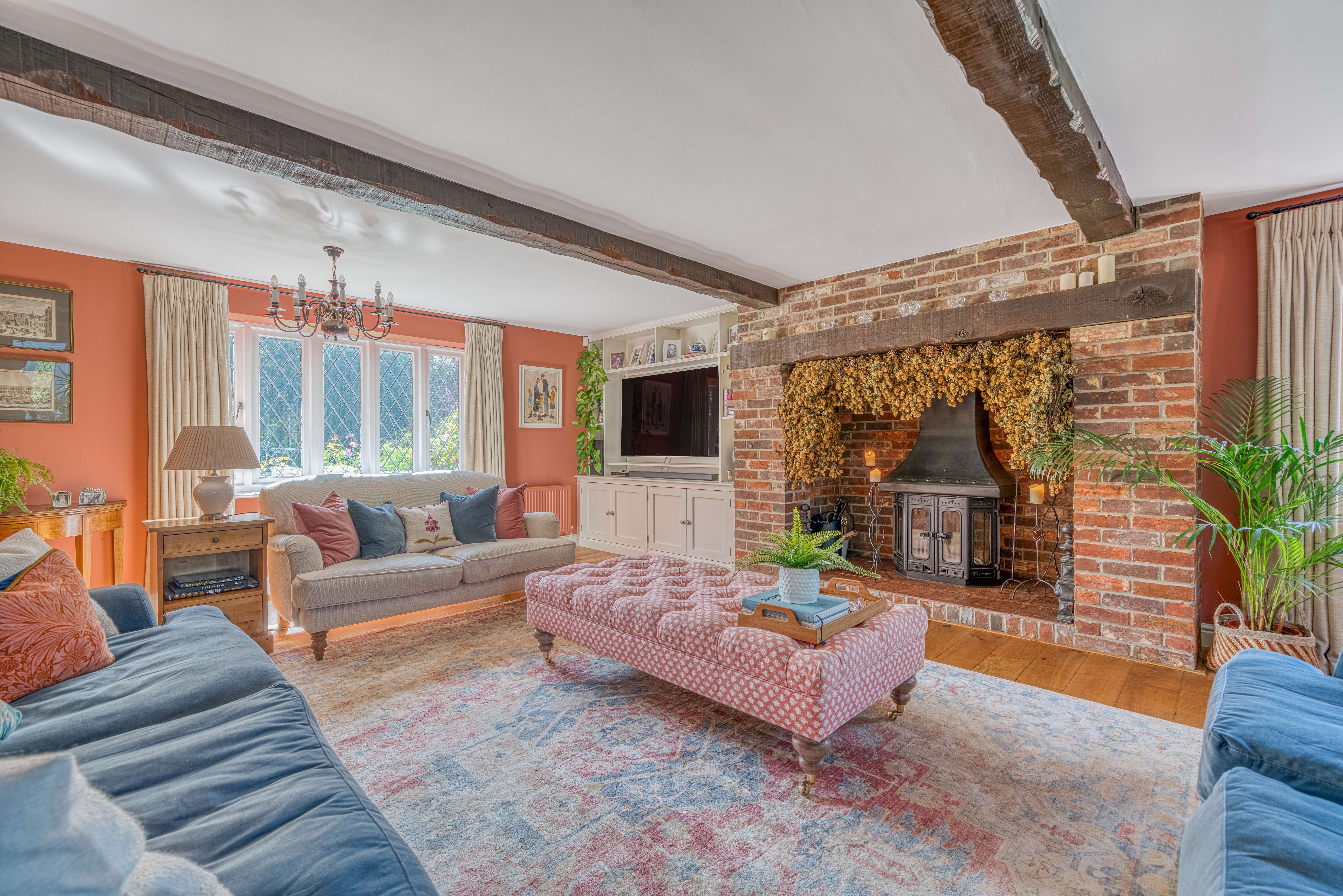 A sitting room in a period style property with sofas facing a central wood burner.