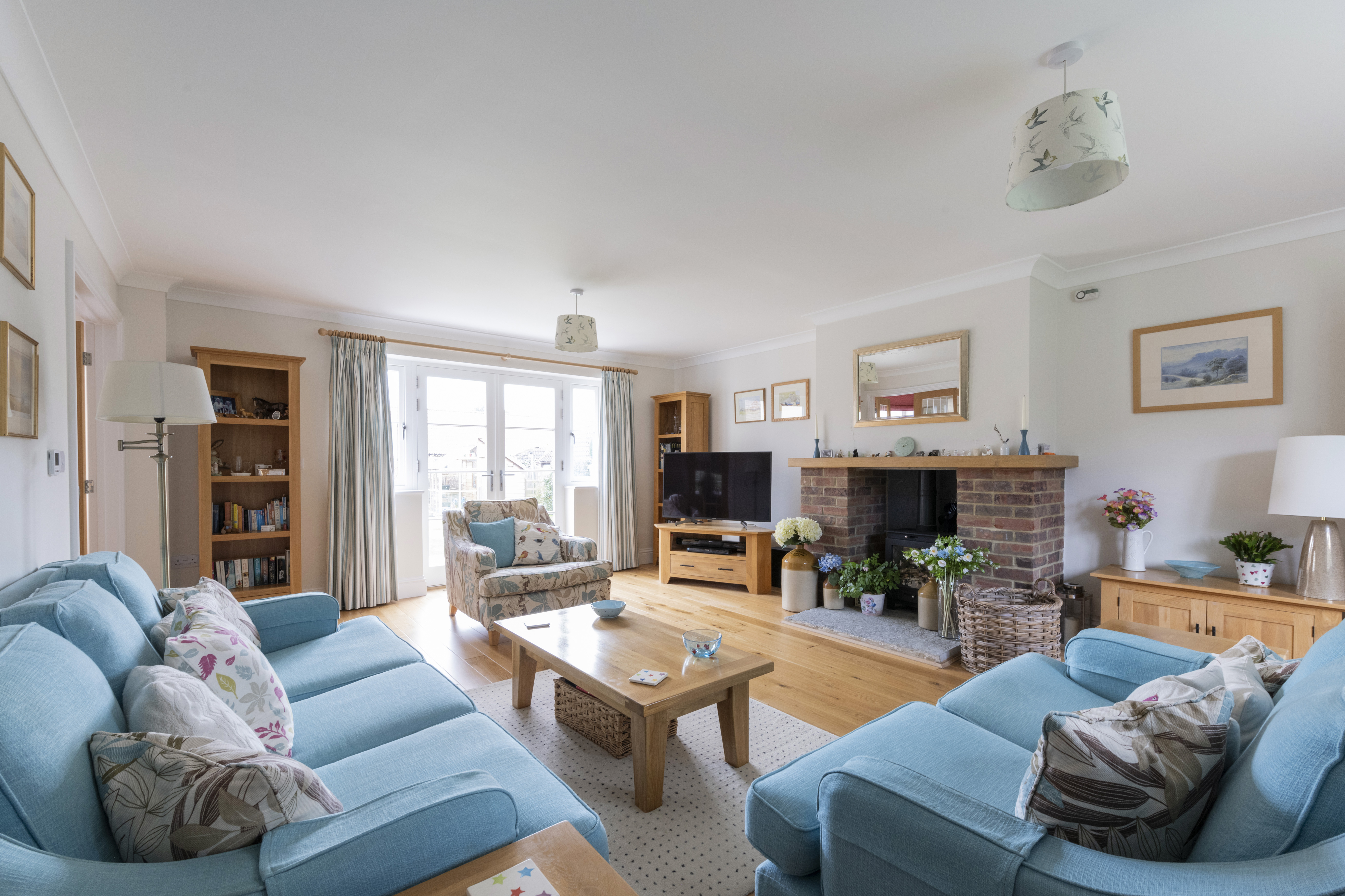 A sitting room in a modern property with sofas facing a central wood burner.