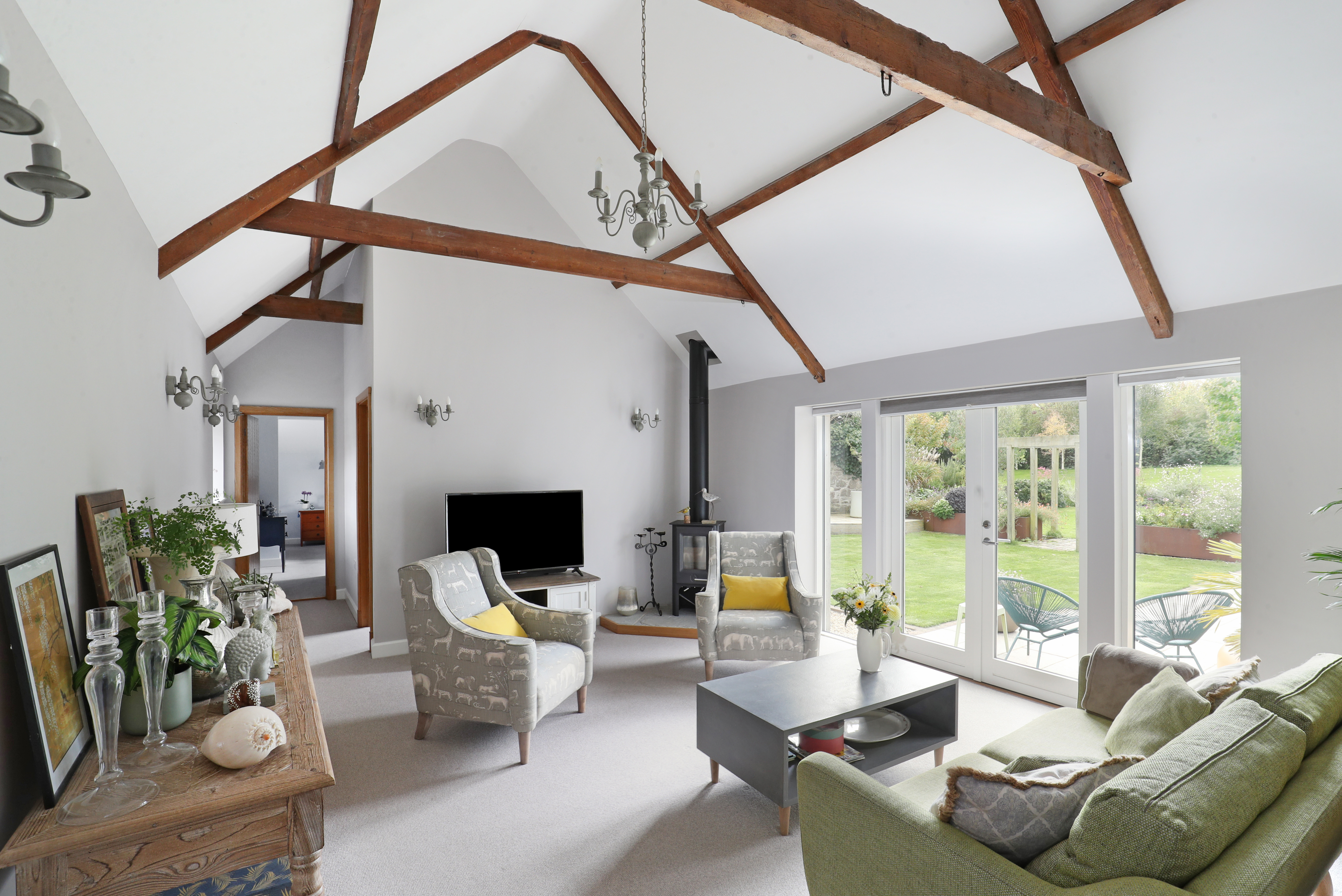 A sitting room with vaulted ceiling in a barn conversion with a seating area and a wood burner.
