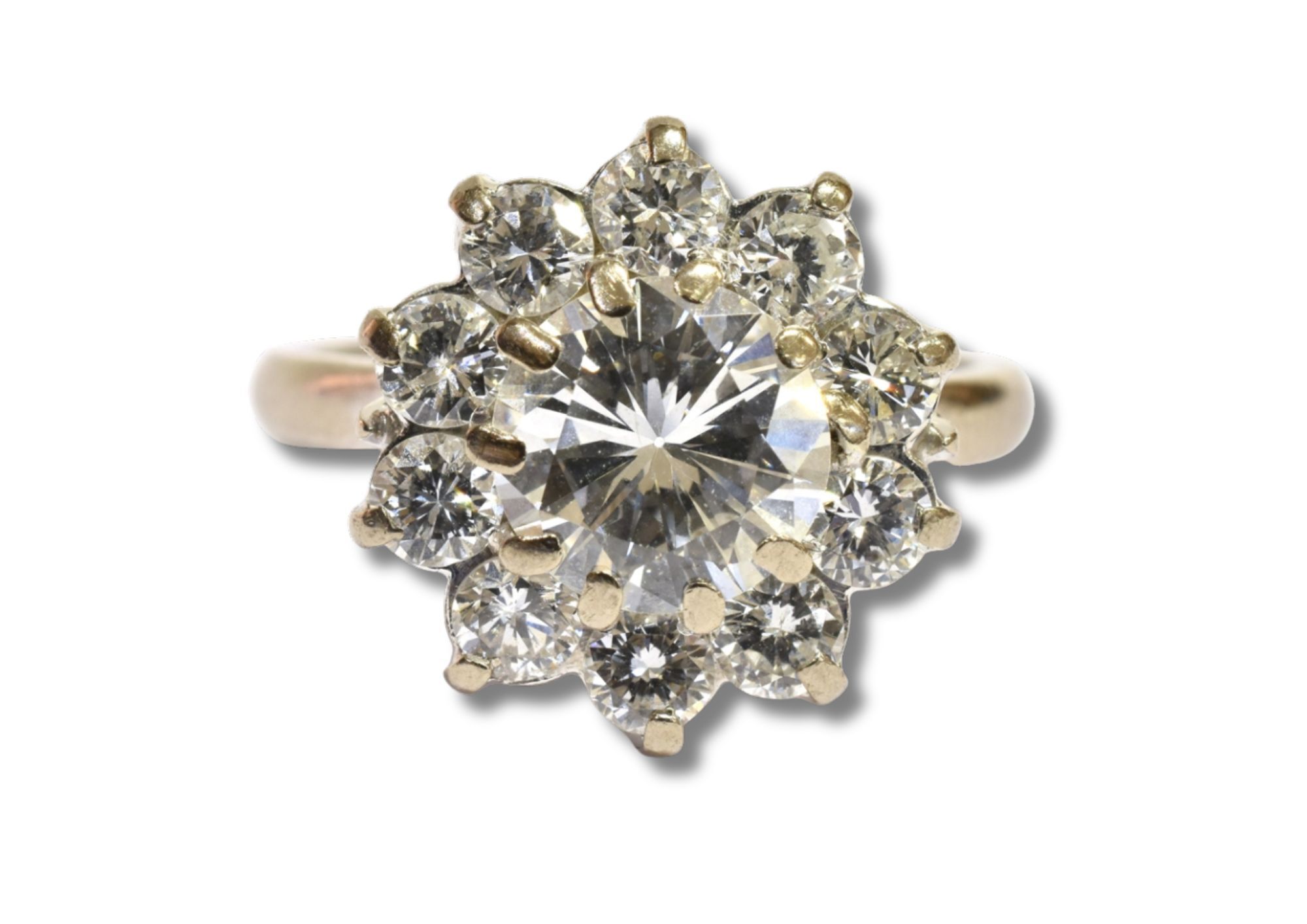 An eighteen carat white gold ring with a round brilliant cut centre stone and ten surrounding cluster stones.