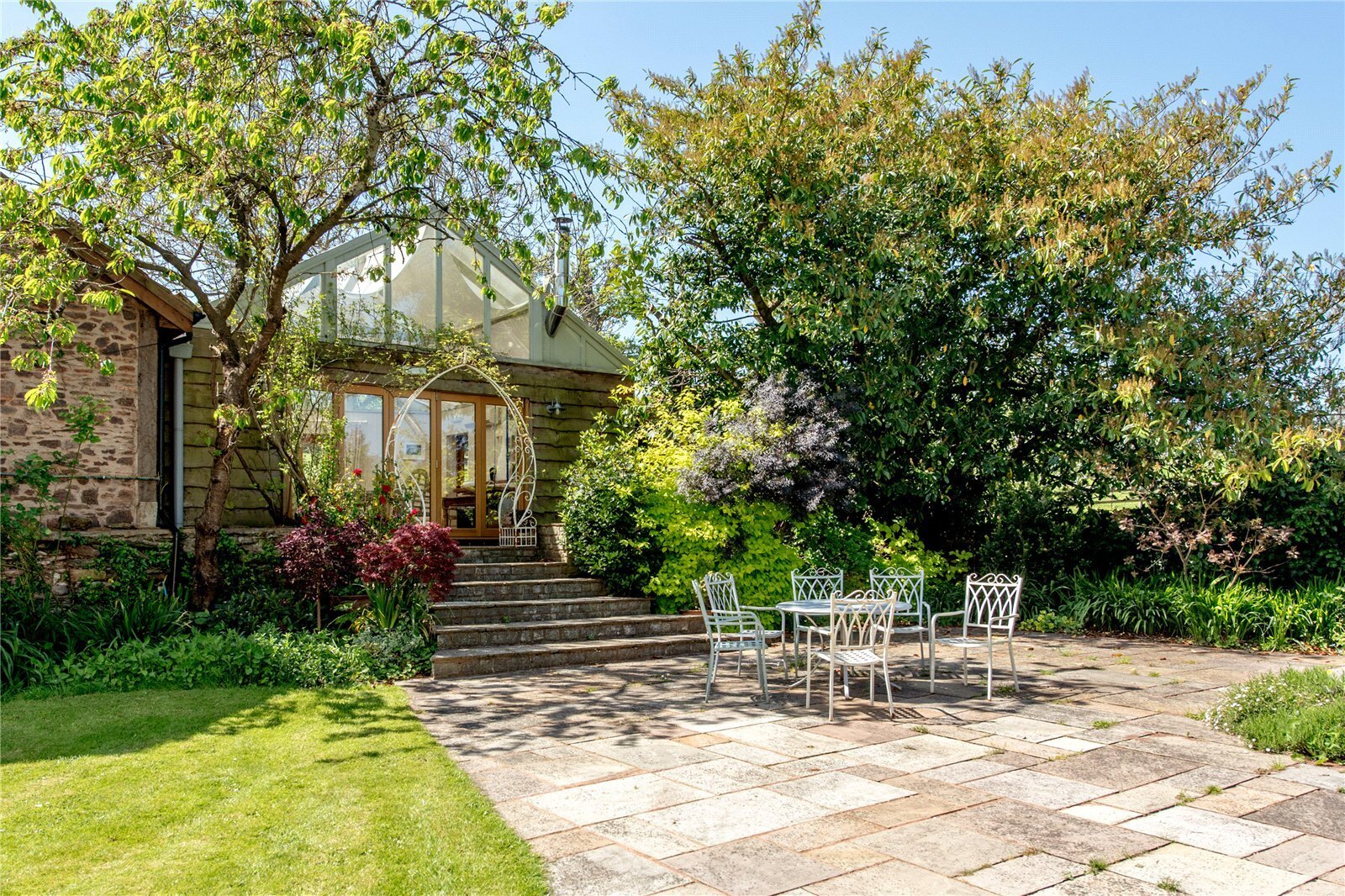 A patioed seating area surrounded by an established garden
