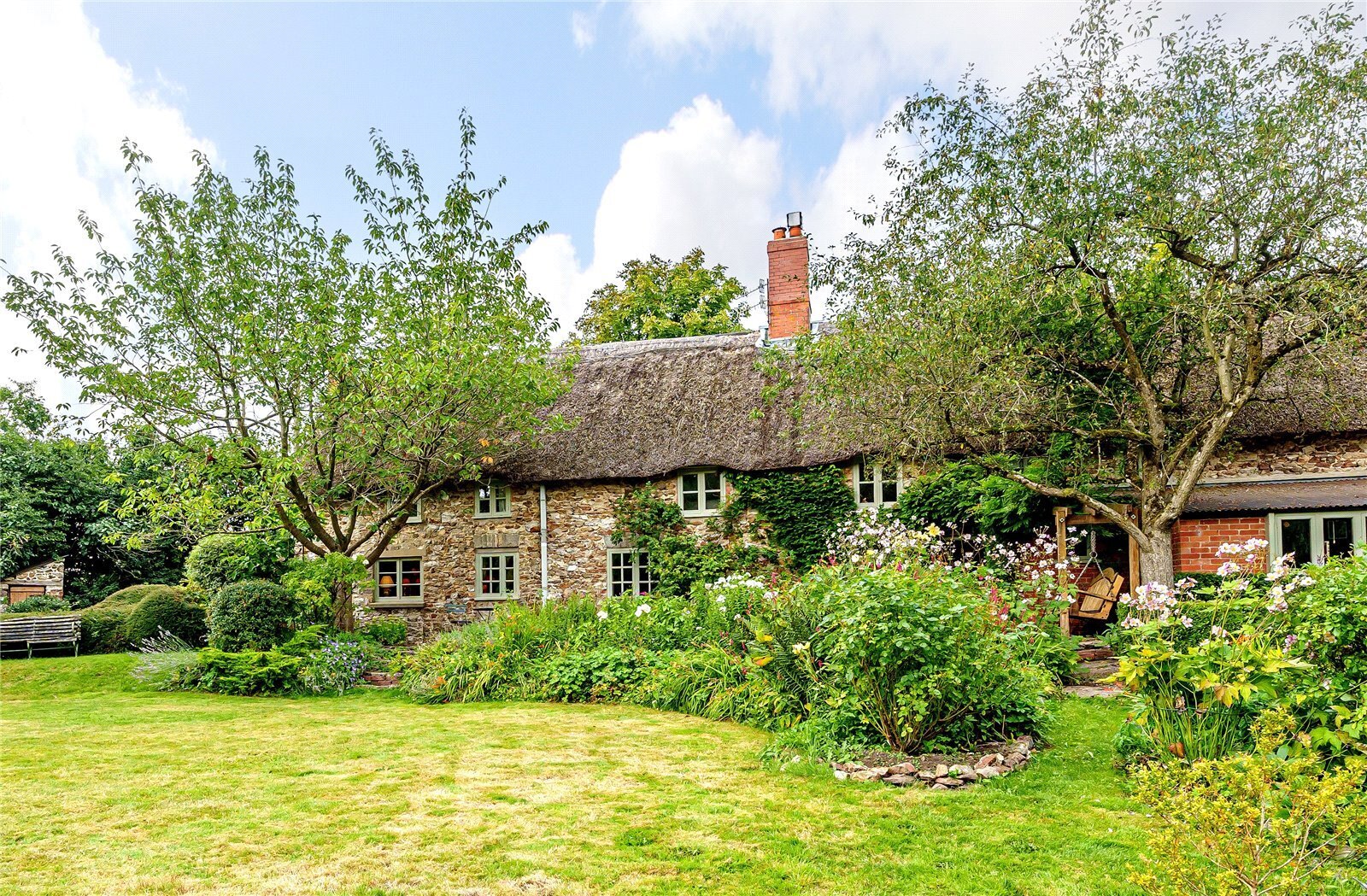 A thatched cottage with a pretty garden in the foreground