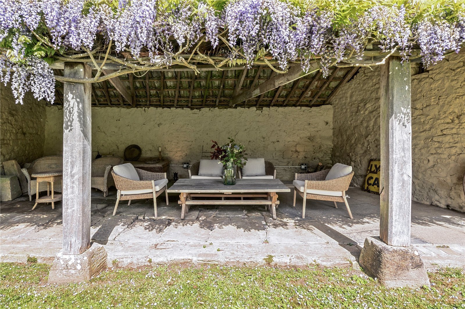 An open sided barn, covered by wisteria with seating inside
