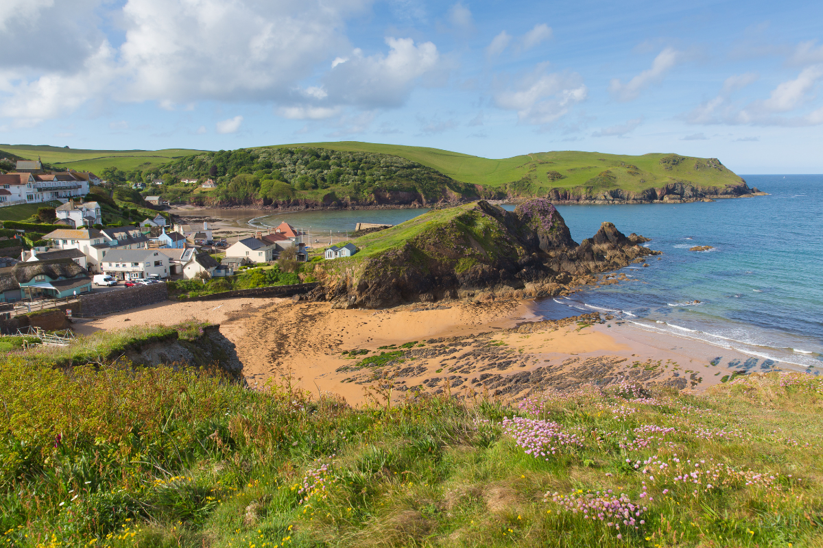 Photo of Hope Cove beach with golden sand, rolling green hills and beautiful green waters