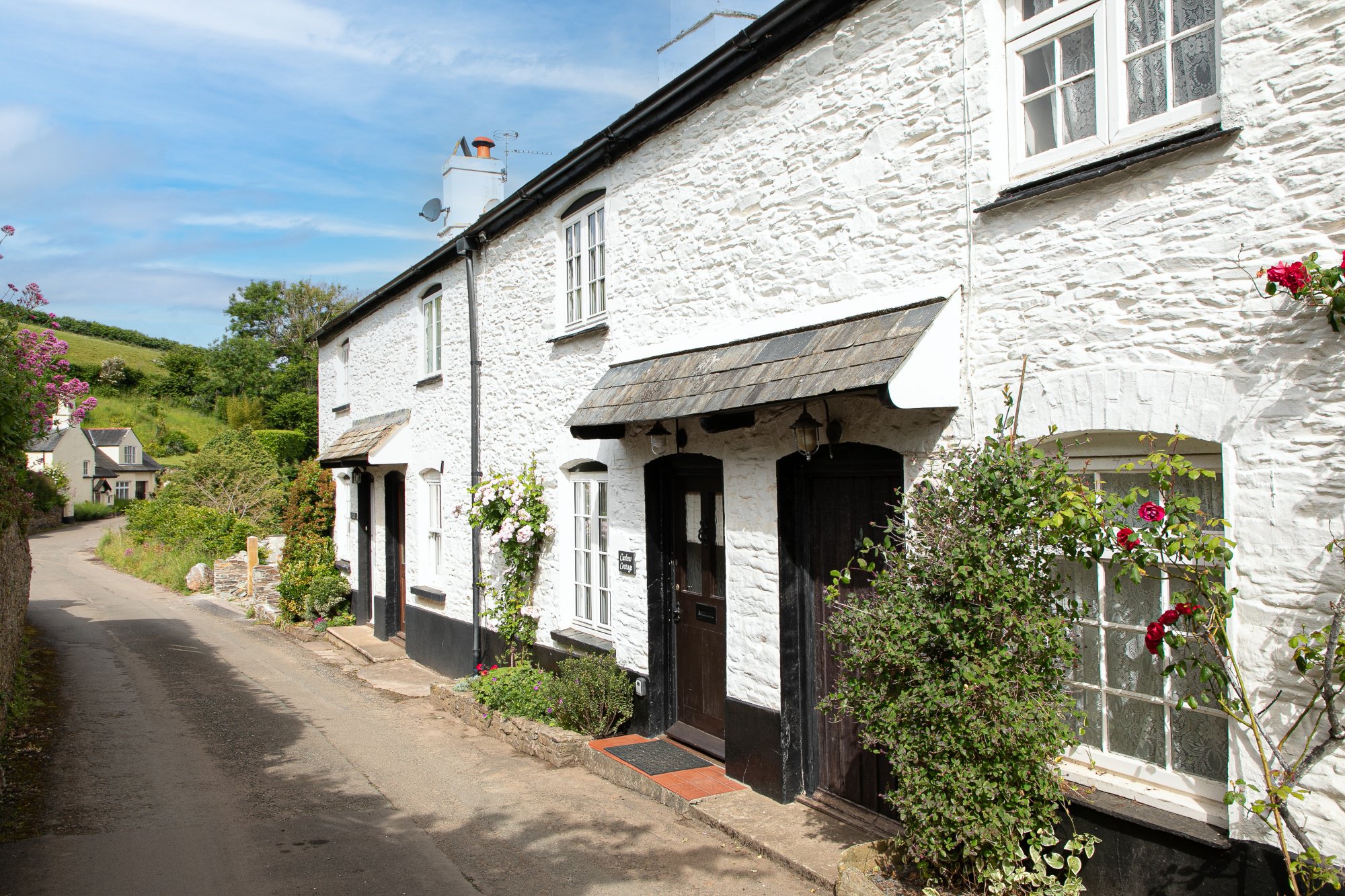 white and black cottage in dittisham country lane, with flowers