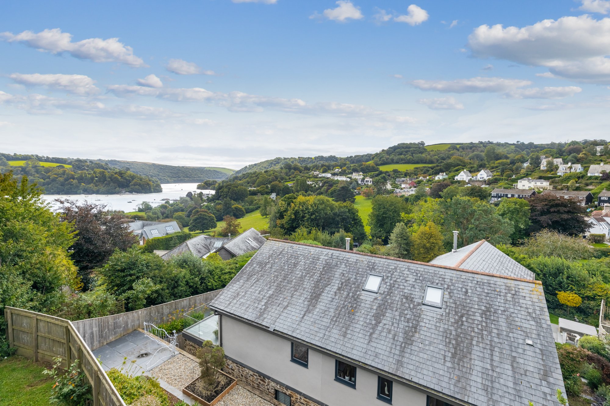large grey house from above overlooking green garden and dart river in dittisham