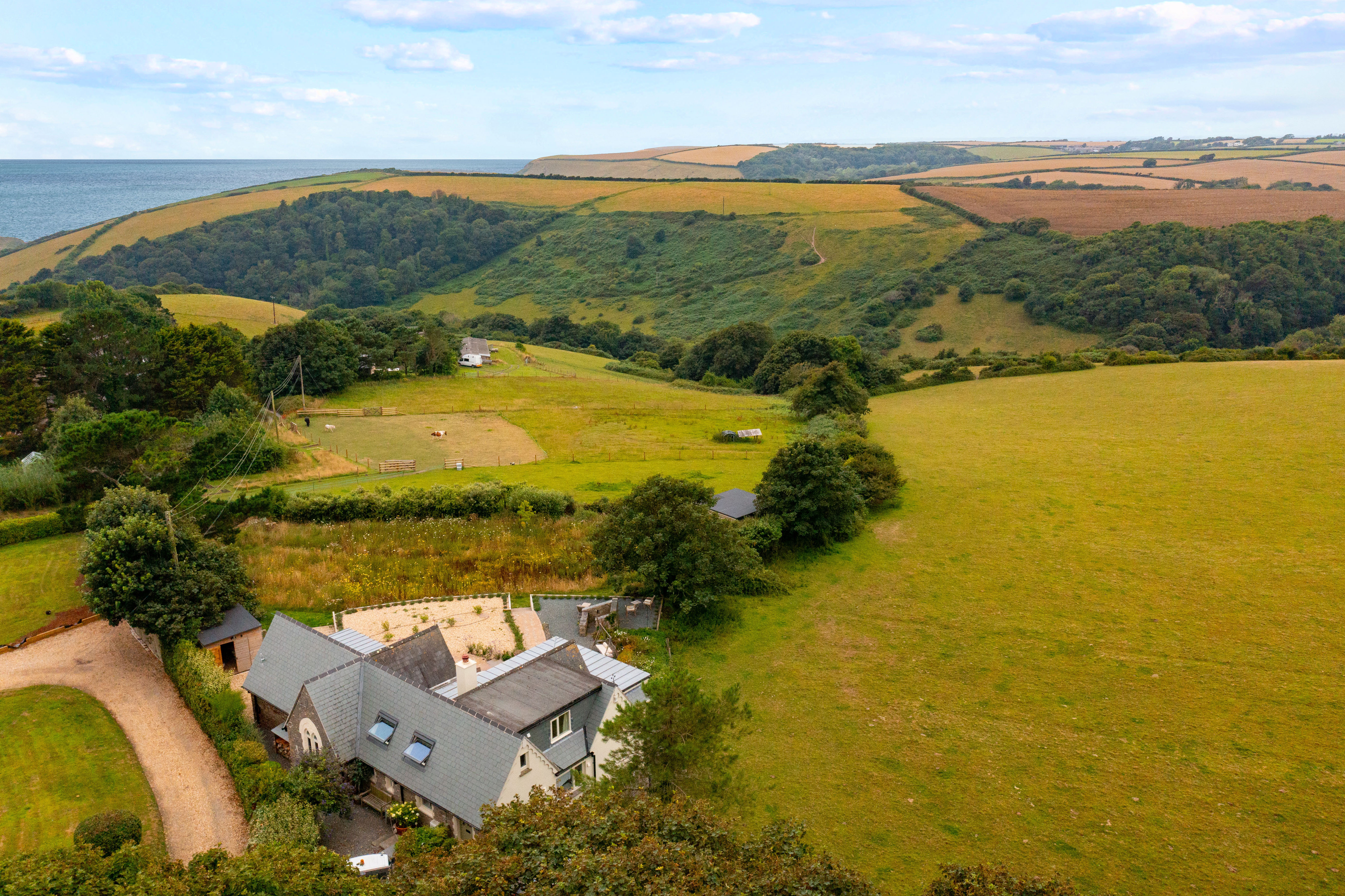 A countryside landscape with the sea and a house