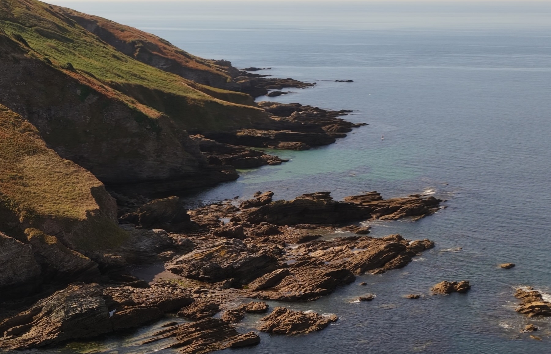 coastal image with jagged cliffs, rocks and blue sea