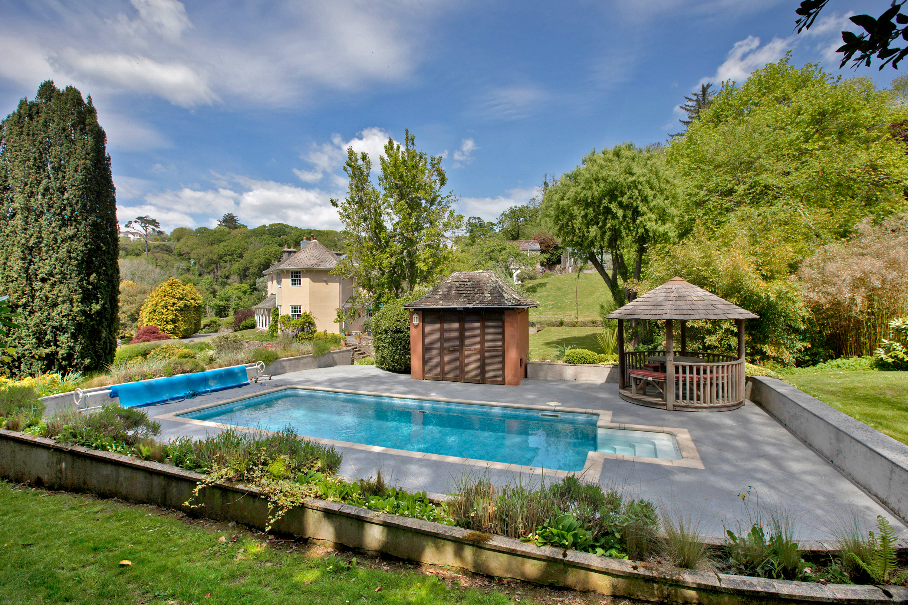 outdoor swimming pool in garden with house in the background