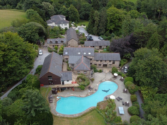 Aerial view of large estate surrounded by trees with a swimming pool