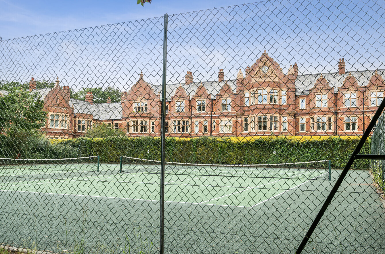 View of tennis court with red brick building in background