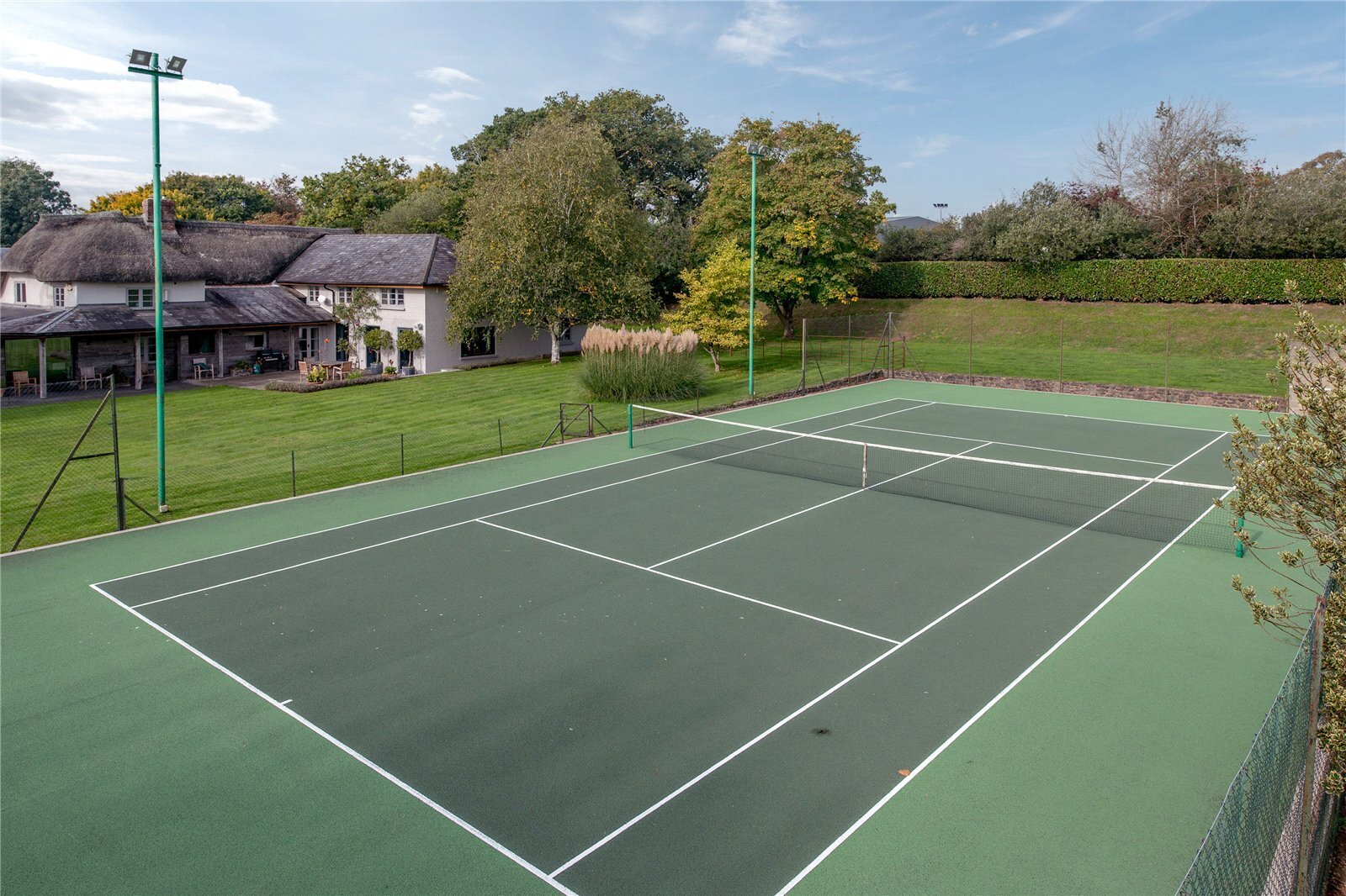 flood lit tennis court in grounds of country house